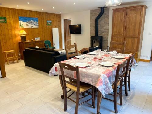 - une salle à manger avec une table, des chaises et un piano dans l'établissement Appartement Spacieux - Terrasse, Jardin et Cheminée - À 5 Min du Centre des Gets - FR-1-623-100, aux Gets
