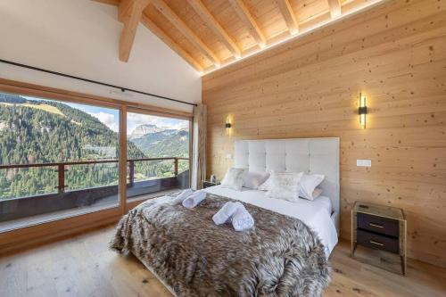 シャテルにあるBlack Diamond - Chalet - BO Immobilier- remises sur les forfaits de skis Châtel ou Portes du soleilのベッドと大きな窓のある寝室
