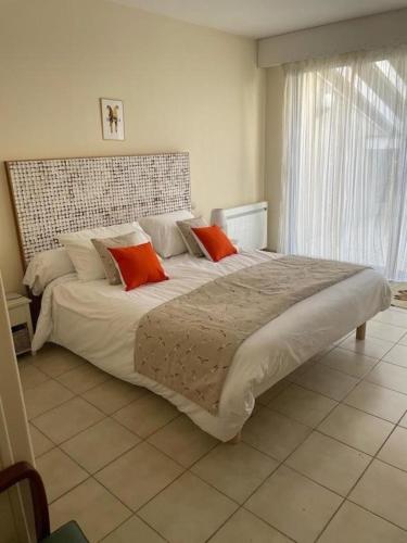 - une chambre avec un grand lit et deux oreillers orange dans l'établissement Villa entre océan et pinède, à La Tremblade
