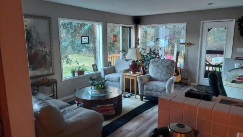 a living room with a couch and chairs and windows at Hidden Valley Bed and Breakfast in Whitehorse