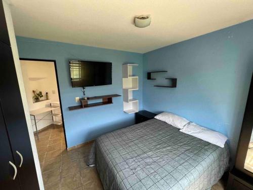 a bedroom with a blue wall with a bed and a television at Casa Deluxe Celaya in Celaya