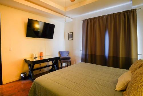 a bedroom with a bed and a desk and a television at Casa Todos Santos with Gated Parking at Casas Sanblu in Ensenada