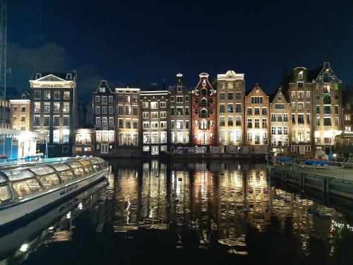 un grupo de edificios con luces en el agua por la noche en KELLY'S ROOM EUPHRATE HOUSEBOAT en Ámsterdam