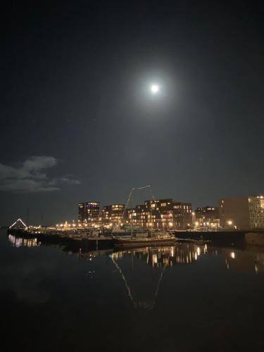 a view of a city at night with the moon at EUPHRATE HOUSeBOAT in Amsterdam