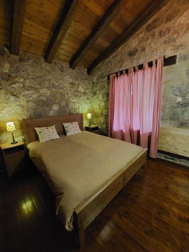 Lilea Country House في Lílaia: غرفة نوم بسرير كبير وستارة وردية