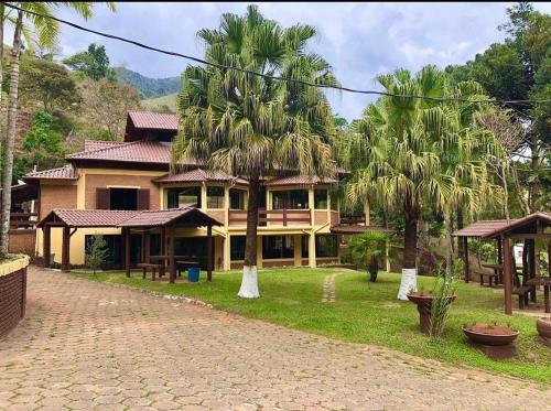 een groot huis met palmbomen ervoor bij hotel fazenda das montanhas in Delfim Moreira