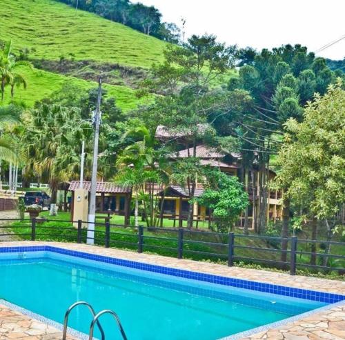 uma piscina em frente a uma casa com uma colina em hotel fazenda das montanhas em Delfim Moreira