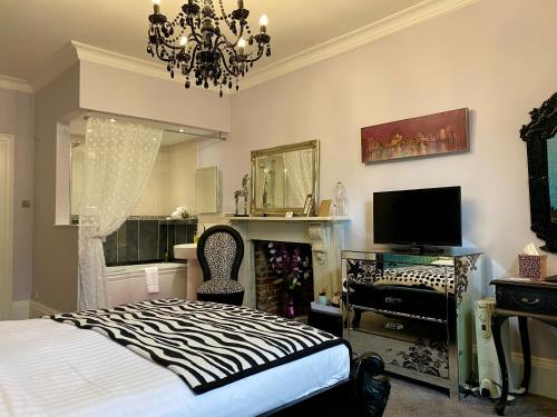 a bedroom with a bed and a television and a chandelier at House of Agnes in Canterbury