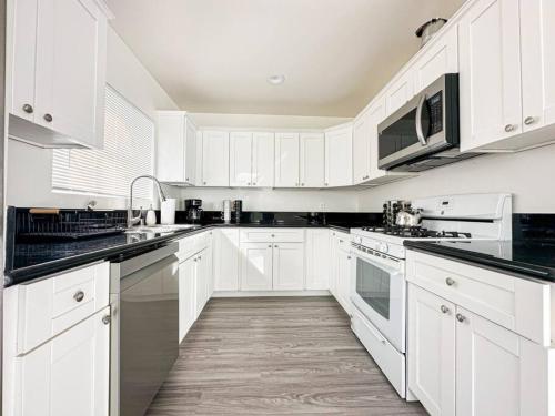 a white kitchen with white cabinets and black counter tops at Modern Friendly 3BR Habitat - WO - BUR in Burbank