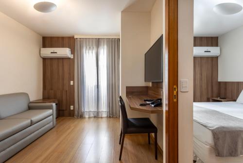 a hotel room with a bed and a couch and a desk at Blue Tree Towers Millenium Porto Alegre in Porto Alegre