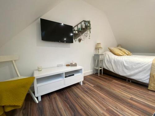 1 dormitorio con 1 cama y TV en la pared en Garden annex en Welton