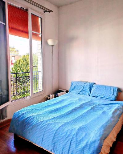 - une chambre avec un lit bleu et une fenêtre dans l'établissement Sean, à Issy-les-Moulineaux