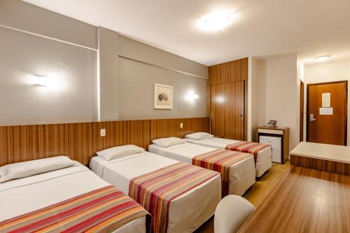 a room with four beds and a table and chairs at Hotel Pires in Balneário Camboriú