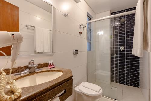 y baño con lavabo, aseo y ducha. en Hotel Pires, en Balneário Camboriú