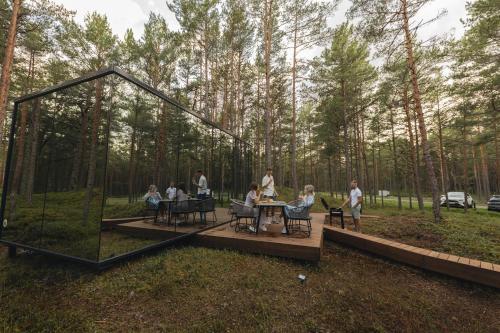 a group of people sitting around a table in the woods at ÖÖD Hötels Lohusalu LEIDA & ENNO in Laulasmaa