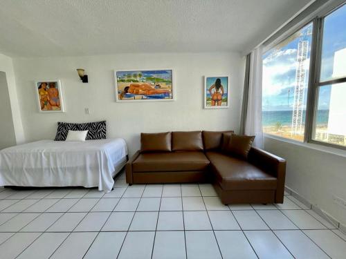 een slaapkamer met een bank, een bed en een raam bij Condado Beachfront Tantra Apartment in San Juan