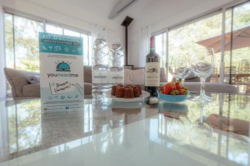 - une table avec deux bouteilles de vin et une assiette de nourriture dans l'établissement Villa A Nouste à Arcachon, à Arcachon