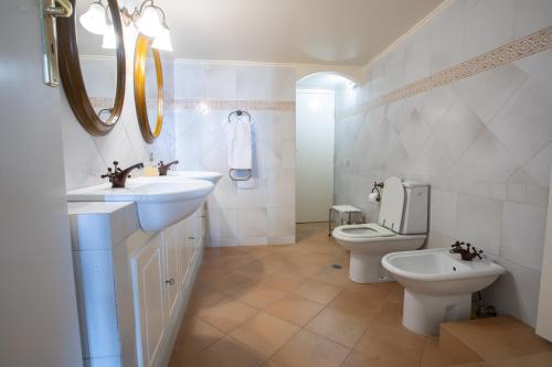 a white bathroom with two sinks and a toilet at Villa Sounio in Sounio