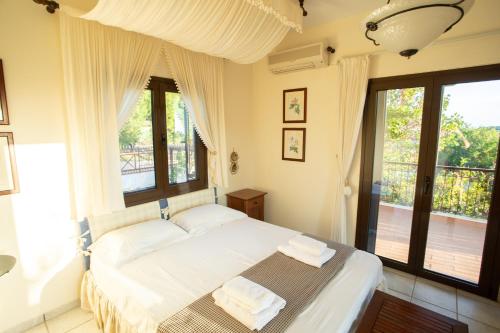 a bedroom with a bed with white sheets and windows at Villa Sounio in Sounio