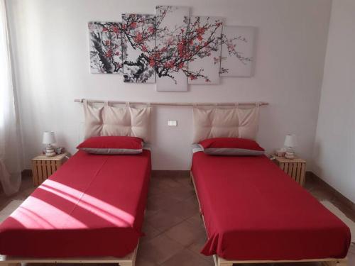 Varallo PombiaにあるGuest House Brera vicino aeroporto di MXP e laghiの赤いシーツが備わるドミトリールームのベッド2台