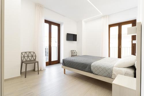 a white bedroom with a bed and a chair at Appartamento comfort-relax in Termoli