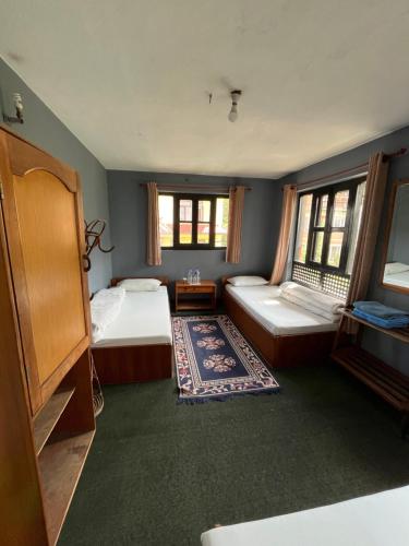 a bedroom with two beds and a tv and windows at Bhaktapur Guest House in Bhaktapur