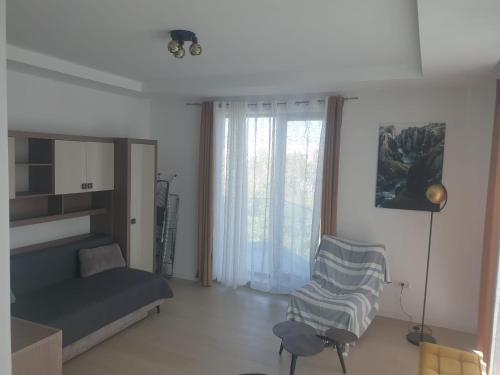 a bedroom with a bed and a chair and a window at Apartament Resort in Constanţa
