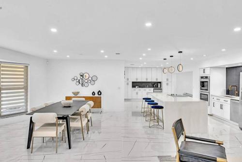 a white kitchen with a dining table and chairs at Luxe 7 Bed Oasis in Hollywood in Hollywood