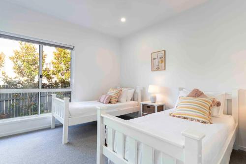 Habitación blanca con 2 camas y ventana en Pet friendly Holiday home with pool on Alex, en Alexandra Headland