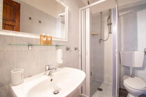 a white bathroom with a sink and a toilet at Hotel Albachiara in Viareggio