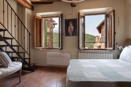 a bedroom with a bed and two windows at Il Borghetto - La Ghibellina Townhouse in Castelnuovo dellʼAbate