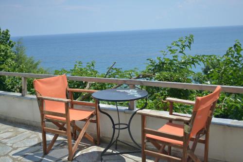 two chairs and a table on a balcony overlooking the ocean at Country Art Studio Alkyoni in Kokkino Nero