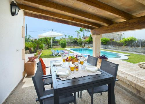 una mesa negra con platos de comida junto a una piscina en Owl Booking Villa Margarita - 15 Min Walk to the Beach, en Puerto Pollensa