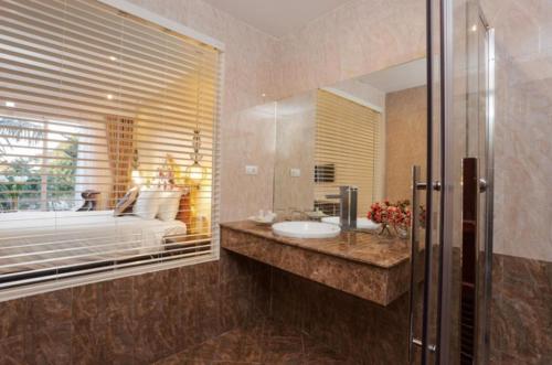 uma casa de banho com um lavatório, uma cama e um espelho. em Xaysomboun Hotel & SPA em Vientiane