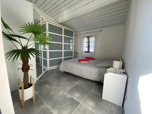 Un dormitorio con una cama y una palmera. en Bienvenue au 6 - Calme et charme de la pierre., en Fourques