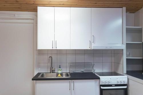 una cocina con armarios blancos y fregadero en B & E Apartment, en Huddinge