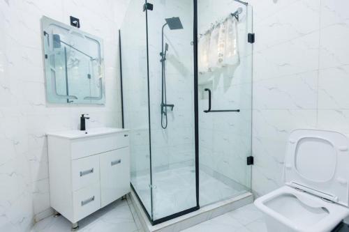 y baño con ducha, aseo y lavamanos. en Rhema Apartments en Lagos