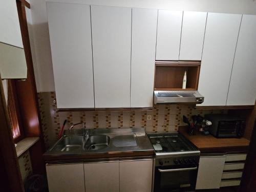 a kitchen with white cabinets and a sink and a stove at La Francigena - Ama's house in Piacenza