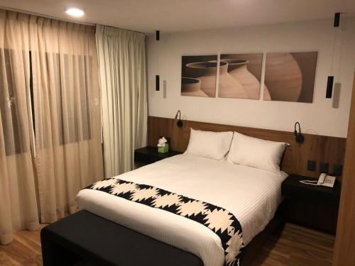 1 dormitorio con 1 cama grande con sábanas blancas en Casa Tlaxcalli by Beddo Hoteles en Tlaxcala de Xicohténcatl