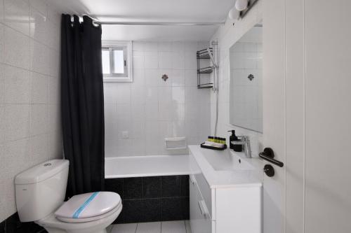 La salle de bains blanche est pourvue de toilettes et d'une baignoire. dans l'établissement Urban Condo 10 - 2 Bdr, à Nicosie