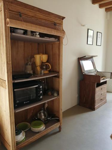 une cuisine avec une étagère en bois avec de la vaisselle et un four micro-ondes dans l'établissement Les chambres de balade au jardin, à Épineu-le-Chevreuil