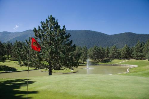 a golf course with a pond and a red flag at Bosques de Monterreal in Mesa de las Tablas