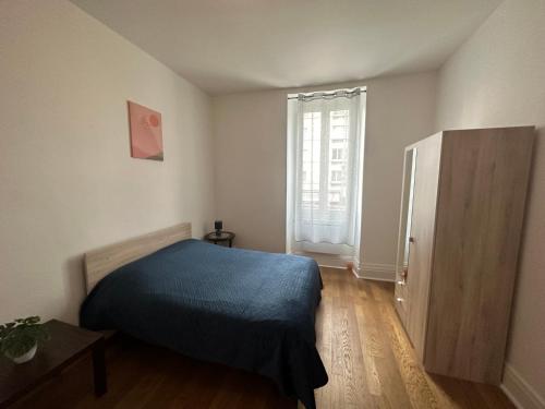 Un dormitorio con una cama azul y una ventana. en Appartement proche de la gare, en Bourges
