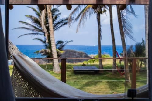 a hammock in a resort with a view of the ocean at Pousada Santú Noronha in Fernando de Noronha