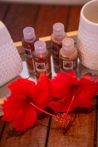 four bottles of honey and a red flower on a table at Pousada Santú Noronha in Fernando de Noronha