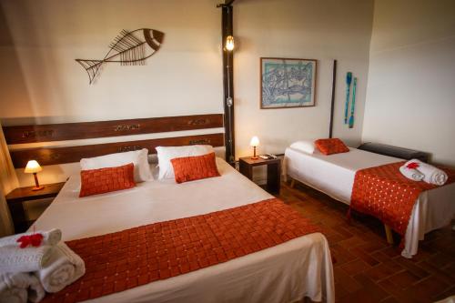 a hotel room with two beds with red pillows at Pousada Santú Noronha in Fernando de Noronha