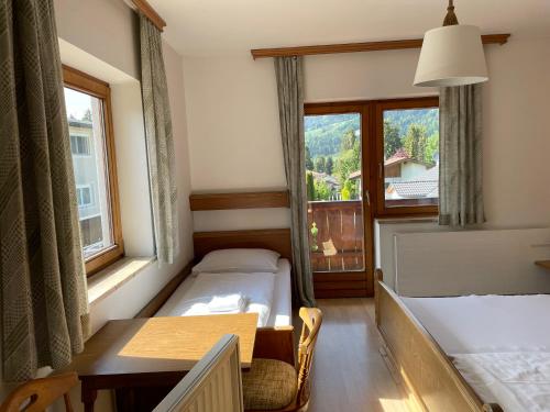 a room with two beds and a table and a window at Pension Kaiserstubn in Söll