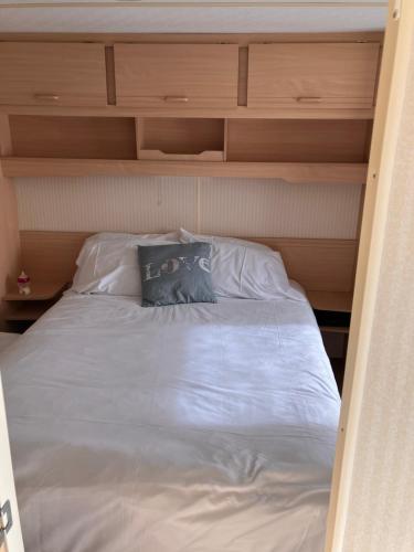 a large bed with white sheets and a blue pillow at Coastal Getaway, camber sands in Camber