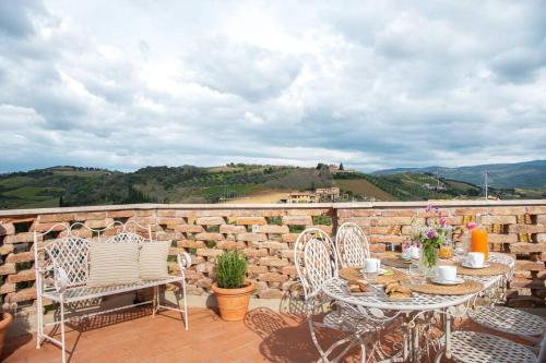 eine Terrasse mit einem Tisch, Stühlen und einer Steinmauer in der Unterkunft Il Borghetto - La Casa di Elba, Terrazzo panoramico in Val d'Orcia in Castelnuovo dellʼAbate