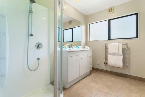 La salle de bains est pourvue d'une douche, d'un lavabo et d'un miroir. dans l'établissement Ultimate 5-Bedroom Rural Poolside Oasis - Auckland, à Albany